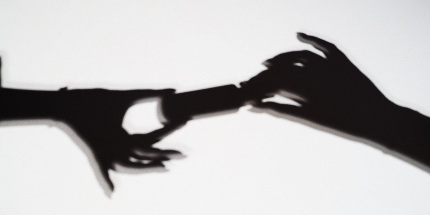 Black silhouette of two hands reaching towards each other on a white background