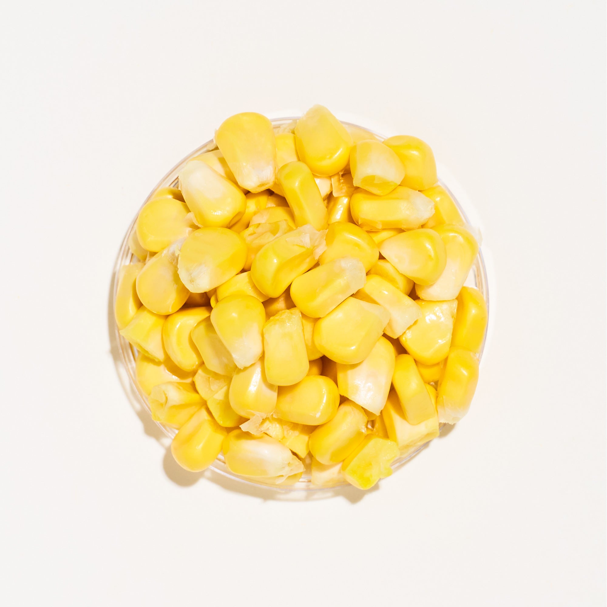 Clear container filled with yellow corn on a white background