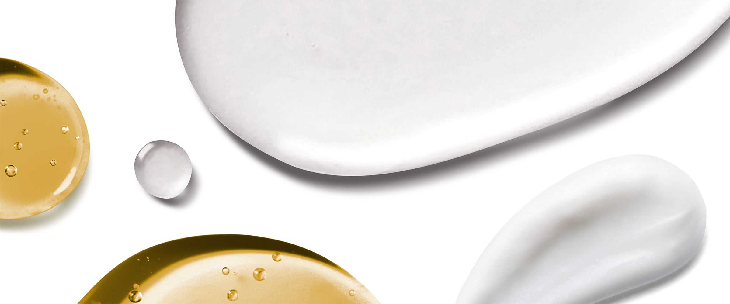 Close-up of white cream and gold oil droplets on a white background